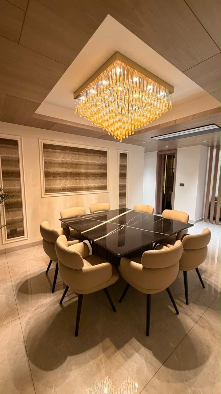 Dining table below a feature chandelier and timber ceiling