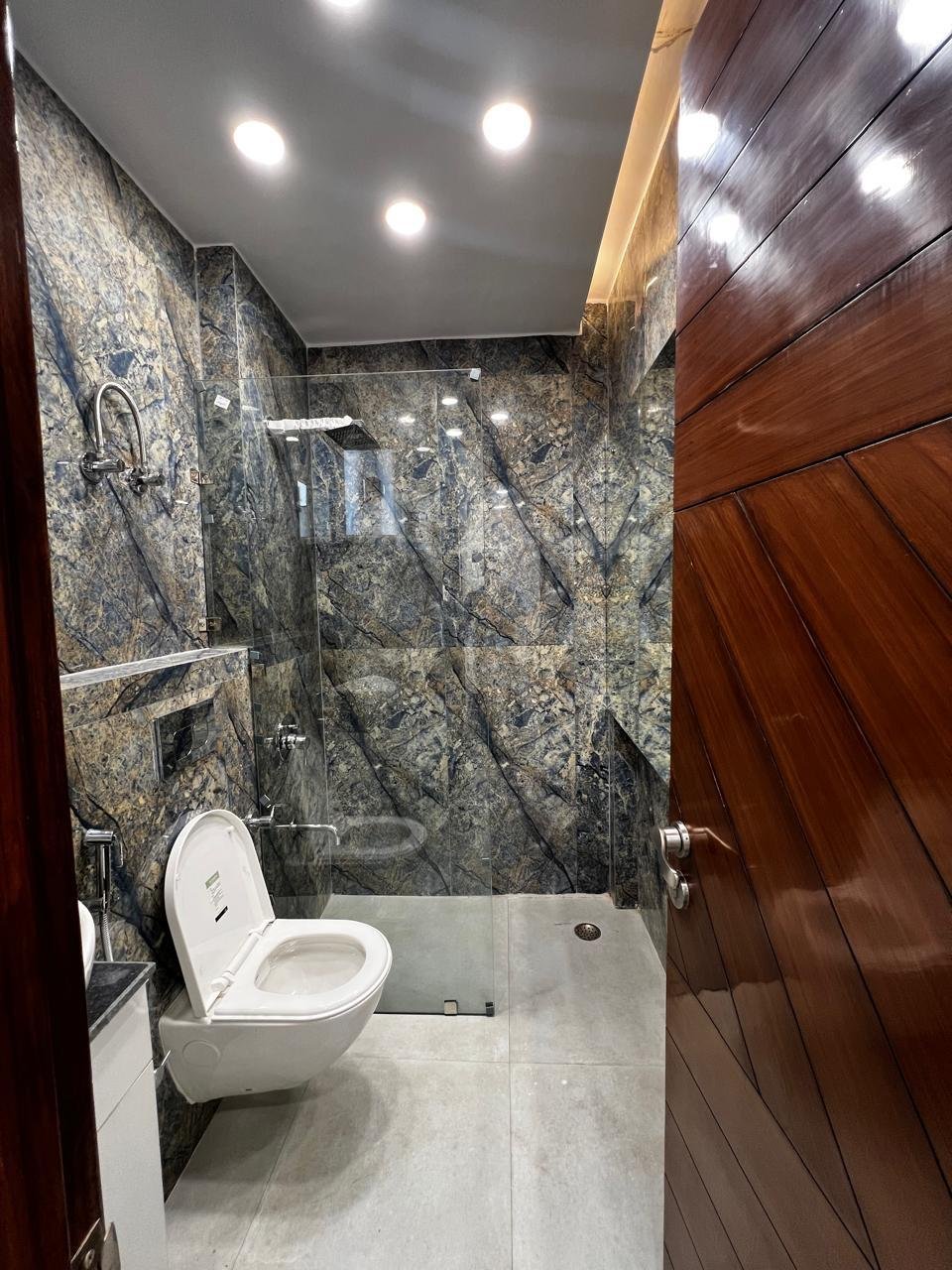 Bathroom with dark stone wall cladding and glass shower