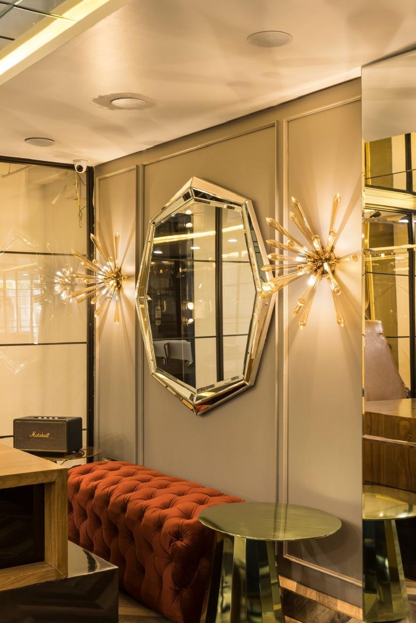 Decorative mirror and wall sconces beside an upholstered bench